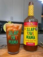 Slap Ya Mama pint glass filled with a beverage, placed next to a bottle of Bloody Mary mix, displayed with a kitchen background 