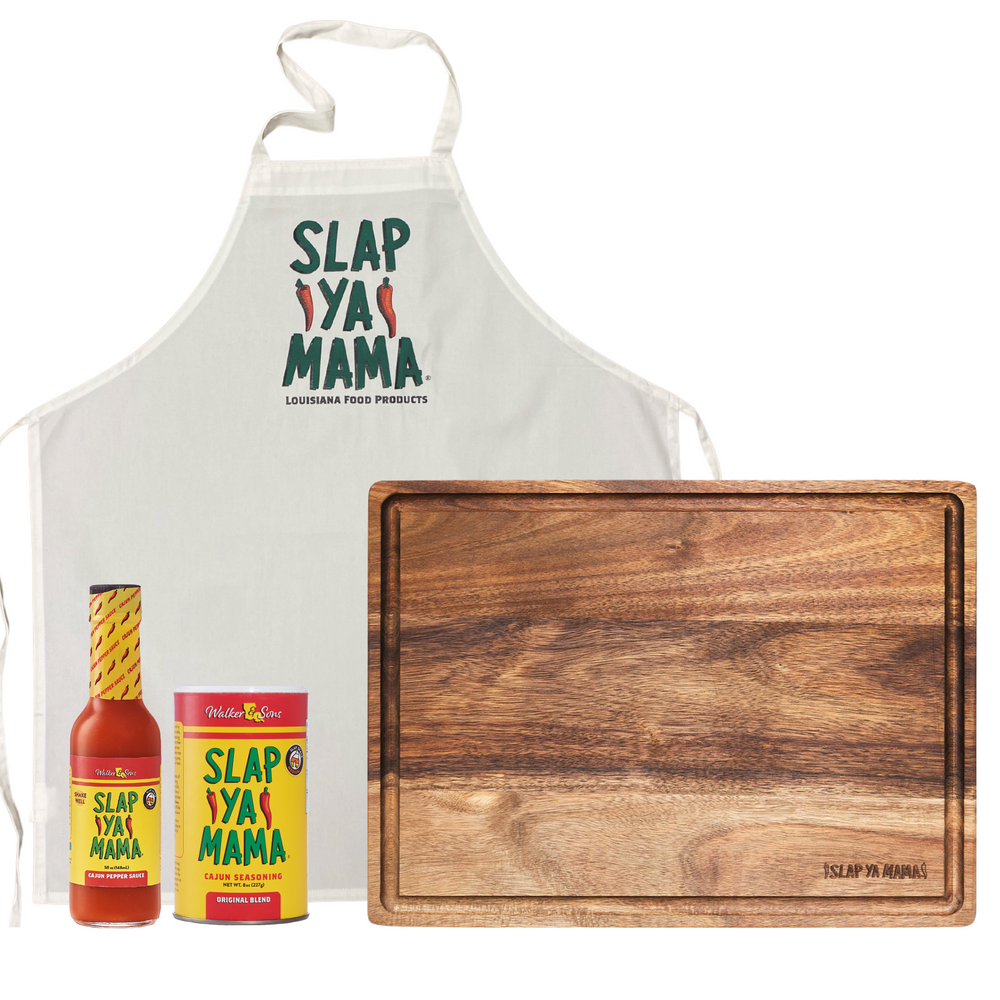 Gift set on a white background featuring a Slap Ya Mama wooden cutting board, a bottle of Cajun Pepper Sauce, an 8oz Original Blend Seasoning can, and a white Slap Ya Mama apron.