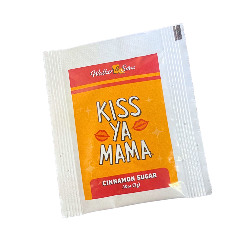 Kiss Ya Mama seasoning packet with a gold label, featuring the white Kiss Ya Mama logo and text reading 'Seasoning Blend' underneath.