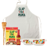 Set includes a Slap Ya Mama Roux Spoon, a Slap Ya Mama Apron, Gumbo Mix, a 5oz bottle of Slap Ya Mama Hot Sauce, an 8oz canister of Slap Ya Mama Cajun Seasoning, and two Slap Ya Mama Gumbo Bowls, all arranged together on a white background.