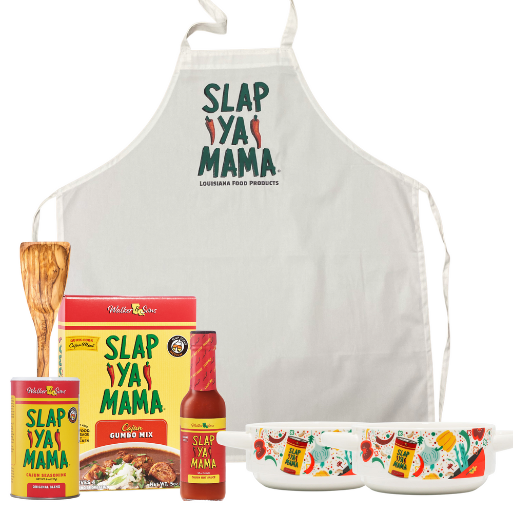 Set includes a Slap Ya Mama Roux Spoon, a Slap Ya Mama Apron, Gumbo Mix, a 5oz bottle of Slap Ya Mama Hot Sauce, an 8oz canister of Slap Ya Mama Cajun Seasoning, and two Slap Ya Mama Gumbo Bowls, all arranged together on a white background.