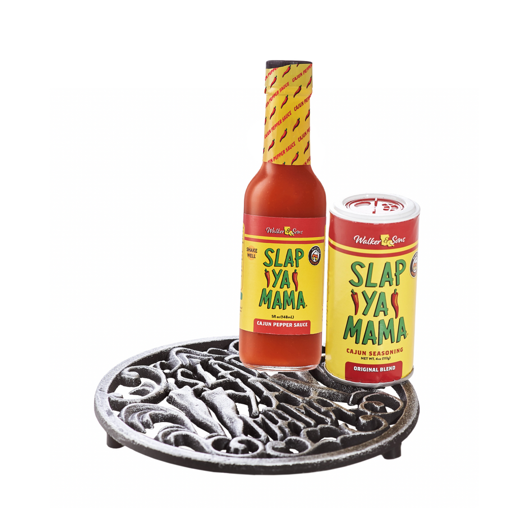 Set includes a 7-inch cast iron trivet with the Slap Ya Mama logo, a 4oz canister of Original Blend Seasoning, and a 5oz bottle of Cajun Pepper Sauce, displayed on a white background.