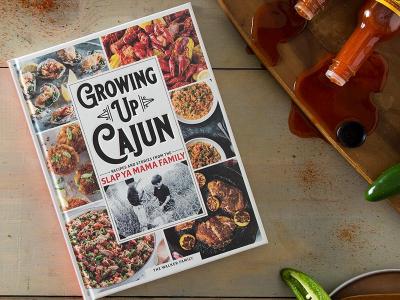 Image of the 'Growing Up Cajun' cookbook with spilled hot sauce and seasoning scattered around it, creating a messy, flavorful scene.