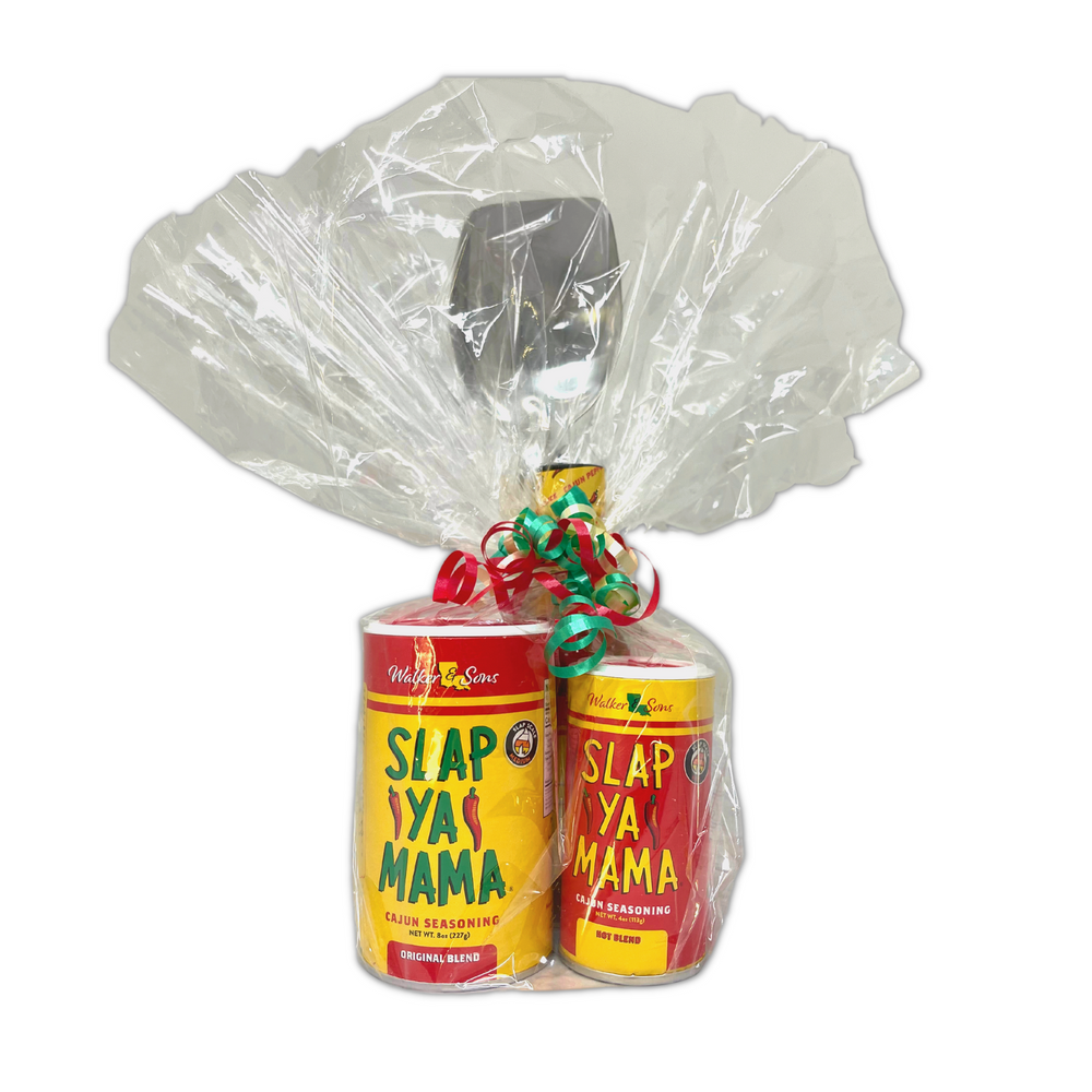 Medal Roux Slap Ya Mama Spoon, 5oz Bottle of Slap Ya Mama Cajun Hot Sauce, 8oz Canister of Slap Ya Mama Original Blend Seasoning, and 4oz Cajun Hot Blend Seasoning, wrapped in clear plastic with a ribbon, displayed on a white background.