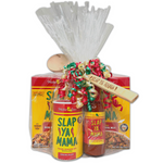 "Gift set featuring a Wooden Slap Ya Mama Spoon, 5oz bottle of Slap Ya Mama Cajun Hot Sauce, 8oz canister of Slap Ya Mama Original Blend Seasoning, Slap Ya Mama Jambalaya Dinner Mix, and Slap Ya Mama Red Beans and Rice Dinner Mix, all wrapped in clear plastic with a ribbon on top."